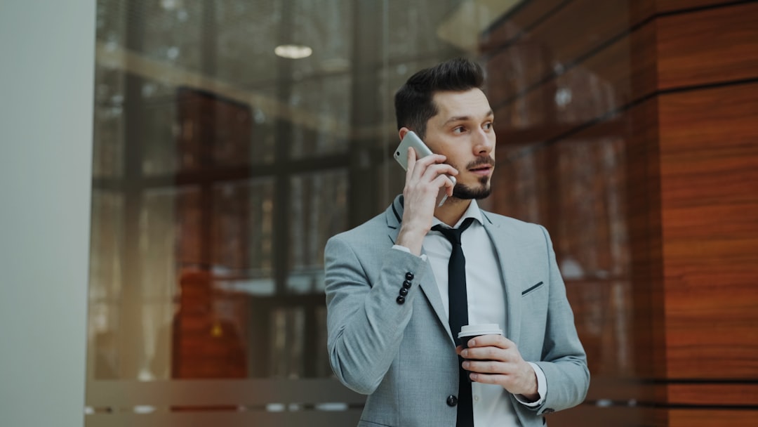 Man in suit talking on phone holding coffee cup